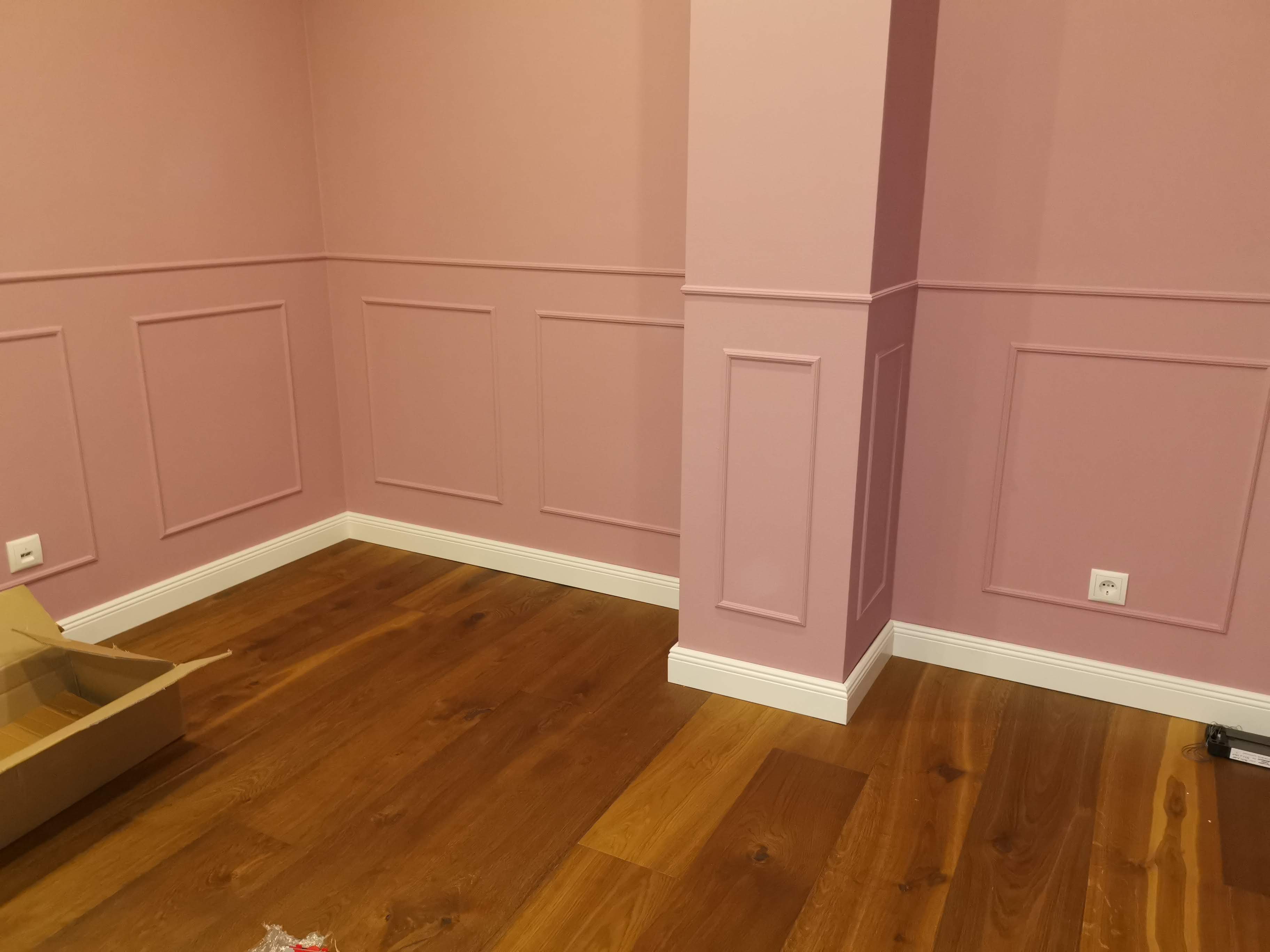 Innenansicht eines rosa gestrichenen Raumes mit Vertäfelung und einem harten Boden